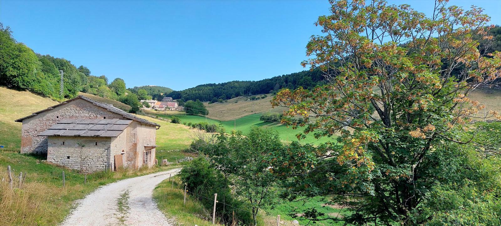 casale rurale in pietra lungo una strada sterrata tra i prati